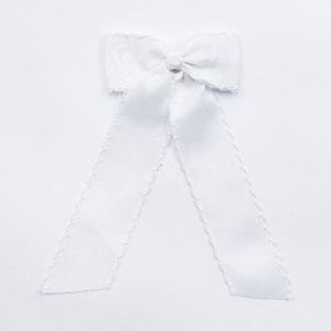 May include: A solid white fabric bow featuring a textured grosgrain ribbon construction with a central knot and two long, downward-hanging tails. The edges of the ribbon are finished with a decorative scalloped trim along the entire length.