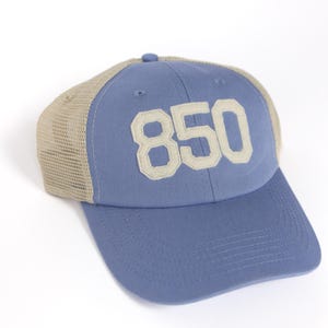May include: A blue and beige trucker hat with the number "850" embroidered on the front in white.