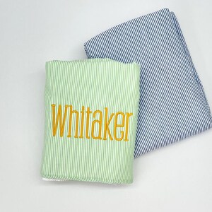May include: Two striped fabric towels, one green and one blue, with the name "Whitaker" embroidered in yellow on the green towel.
