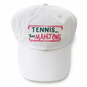 May include: White baseball cap with the embroidered text "TENNIS... Then MAH JONG" in green and pink. The text is inside a pink rectangular border. The cap has a curved brim and a button on top.