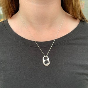 May include: A silver chain necklace with a silver pull tab pendant.