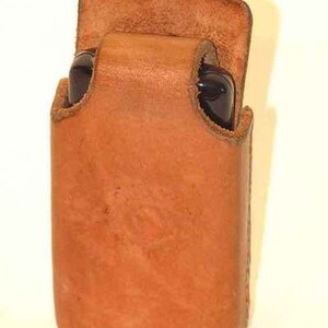May include: A brown leather case for a cell phone or other small electronic device.
