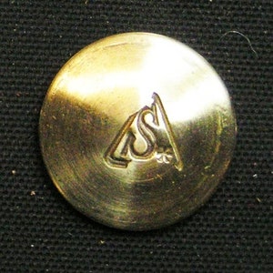 May include: A gold-colored metal button with the letters "LSI" embossed in a triangle shape.