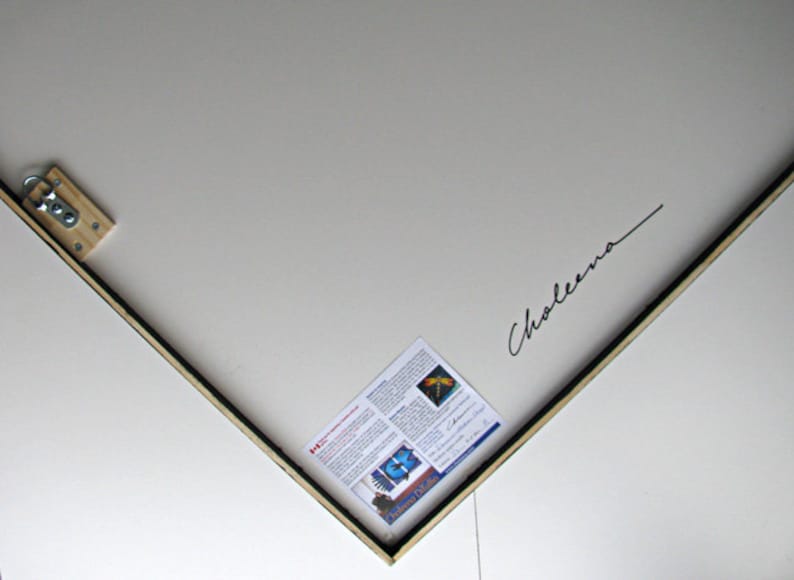 May include: A corner view of a white canvas with a black frame. A wooden support with a metal ring is attached to the top left corner. A small paper with text and a butterfly image is attached to the canvas. The signature "Choleena" is written in black.
