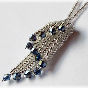 May include: A silver chain necklace with a pendant made of silver beads and blue crystal beads. The pendant is shaped like a teardrop and hangs from the chain.