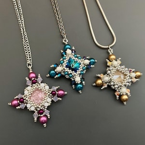 Op de afbeelding: Drie zilveren kettingen met stervormige hangers. De hangers zijn gemaakt van kralen in verschillende kleuren, waaronder roze, blauw, goud en wit.