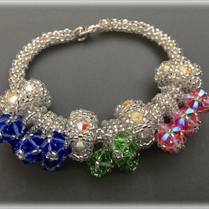 May include: A silver beaded bracelet with a silver clasp and colourful crystal beads. The beads are in shades of blue, green, pink, and white.