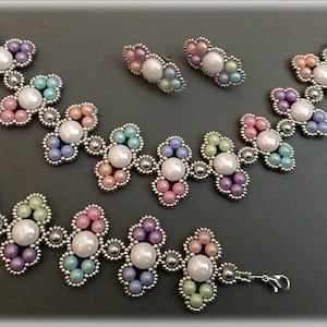 Könnte beinhalten: Ein Schmuckset mit Halskette, Armband und Ohrringen. Die Teile sind aus silberfarbenem Metall gefertigt und mit Clustern aus pastellfarbenen Perlen und großen, perlmuttfarbenen weißen Perlen verziert. Das Armband hat einen Verschluss.