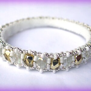 May include: A white beaded bangle bracelet with gold and clear glass beads.