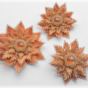May include: Three peach-colored beaded flower brooches with silver accents and clear crystal centers.