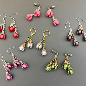 May include: Assortment of handmade earrings featuring various colors and styles. The earrings are made with beads and feature a flower design.