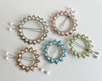 Könnte beinhalten: Fünf Perlen-Haarklammern in verschiedenen Farben, jede mit einem runden Design und zwei Metallzinken. Die Farben sind rosa, blau, grün, braun und silber.