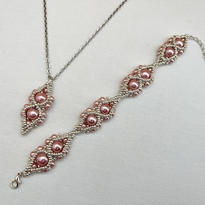 Puede incluir: Un delicado conjunto de collar y pulsera de plata con cuentas de perlas rosas en un patrón geométrico.