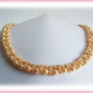 May include: A double-strand necklace made with gold and cream-coloured beads. The necklace is made with small, round beads and larger, round beads.