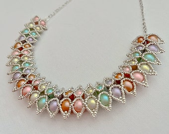 May include: A delicate silver chain necklace with a multi-colored beaded design. The beads are arranged in a graduated pattern, creating a cascading effect. The necklace is made with pastel pink, green, and purple beads.