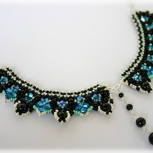 Pode incluir: Um colar de contas pretas e azuis com um pingente em forma de lágrima. O colar é feito de contas pequenas e redondas e tem uma borda festonada.