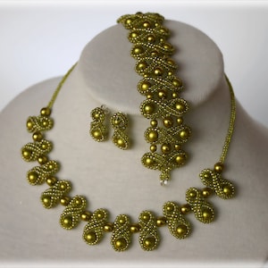 May include: A green beaded jewelry set with a necklace, bracelet, and earrings. The jewelry is made of small, round beads that are strung together in a pattern of loops and swirls.