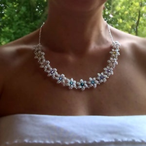 May include: A silver beaded necklace with white flower-shaped beads and colourful gemstone accents.