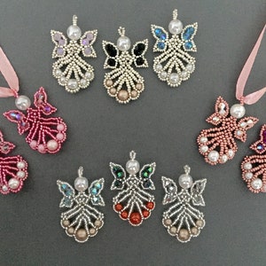 May include: Nine beaded angel ornaments with different coloured wings and pearl accents. The angels are hanging from pink ribbon.