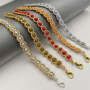 May include: Five beaded bracelets with gold chain links and different coloured beads. The bracelets are arranged in a row, with the lightest coloured bracelet at the top and the darkest coloured bracelet at the bottom. The bracelets are all made with the same pattern of beads.