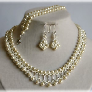 Może przedstawiać: Zestaw biżuterii z pereł w kolorze kości słoniowej, w skład którego wchodzi naszyjnik, bransoletka i kolczyki. Naszyjnik i bransoletka wykonane są z małych i dużych pereł, a kolczyki mają kształt łzy.