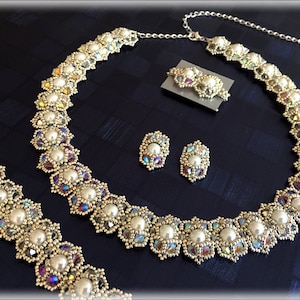 May include: A silver necklace and matching earrings with iridescent crystals and white pearls. The necklace is a long, delicate chain with a pendant that features a cluster of crystals and pearls. The earrings are small and simple, with a single crystal and pearl.