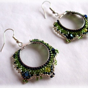 May include: A pair of silver hoop earrings with green, black, and silver beads. The earrings have a starburst design.