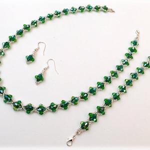 May include: A green crystal necklace, bracelet, and earrings set. The jewelry is made with faceted green crystals and silver-toned metal.