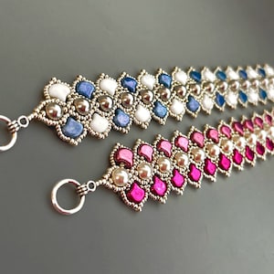 May include: Two beaded bracelets with silver accents. One bracelet features blue, white, and silver beads, while the other features pink, white, and silver beads.