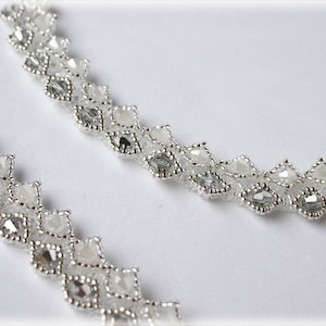 May include: Two strands of silver beaded jewelry with clear crystal beads arranged in a diamond pattern.