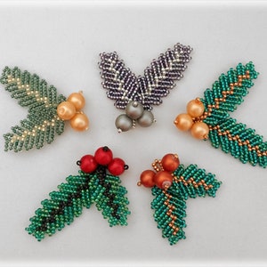 May include: Five beaded holly sprigs with different colored berries. The sprigs are made with green, gold, and silver beads. The berries are red, orange, and gold.