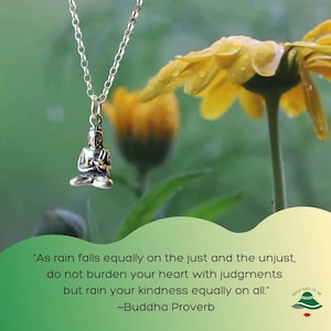 Può includere: Una collana d'argento con un piccolo ciondolo di Buddha in meditazione. La collana è appesa su uno sfondo di un fiore giallo con foglie verdi. La citazione "Come la pioggia cade ugualmente sul giusto e sull'ingiusto, non appesantire il tuo cuore con giudizi, ma fai piovere la tua gentilezza ugualmente su tutti." ~Proverbio di Buddha è visualizzata sotto l'immagine.