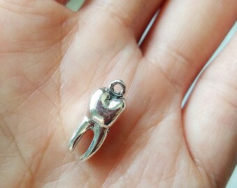 May include: Silver charm in the shape of a tooth. The charm is detailed and realistic, with a smooth, polished finish.