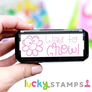 May include: A black and white self-inking stamp with a pink flower and the text "Way to Grow!" in pink lettering.