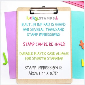 K&ouml;nnte beinhalten: Ein wei&szlig;er Klemmbrett mit dem Text "lucky STAMPS" in bunten Buchstaben. Der Text "BUILT-IN INK PAD IS GOOD FOR SEVERAL THOUSAND STAMP IMPRESSIONS" ist in Schwarz geschrieben. Der Text "STAMP CAN BE RE-INKED" ist in Pink geschrieben. Der Text "DURABLE PLASTIC CASE ALLOWS FOR SMOOTH STAMPING!" ist in Gr&uuml;n geschrieben. Der Text "STAMP IMPRESSION IS ABOUT 1" X 2.75" ist in Grau geschrieben.