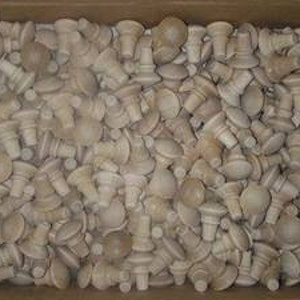 May include: A box filled with a large quantity of small, unfinished wooden knobs. The knobs are a light brown color and have a rounded top with a small stem.