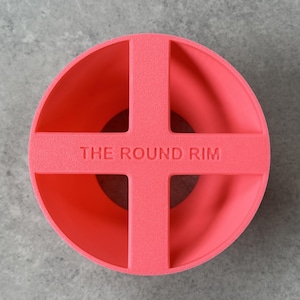 May include: A bright pink plastic ring with four open sections, labeled "THE ROUND RIM".