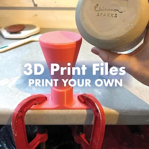 Könnte beinhalten: Ein leuchtend rosa 3D-gedrucktes Werkzeug mit einem ausgestellten Oberteil und einer rechteckigen Basis, das mit zwei roten Metallschraubzwingen an einer Oberfläche befestigt ist. Der Text "3D Print Files PRINT YOUR OWN" ist in Weiß überlagert.