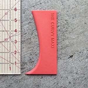 May include: A bright pink plastic tool called "The Curvy Maxi" for smoothing out fondant or icing.