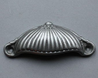 May include: A silver metal cabinet pull with a fluted design. The pull has a rounded top and two small holes on either side.