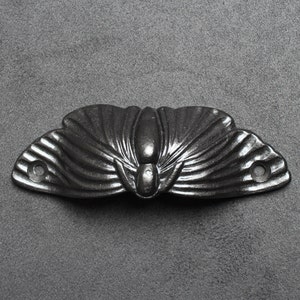 May include: Black cast iron butterfly drawer pull with a detailed design.