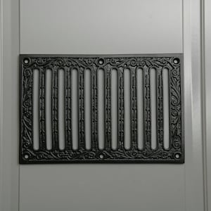 May include: Black cast iron vent cover with a decorative floral design and vertical bars.