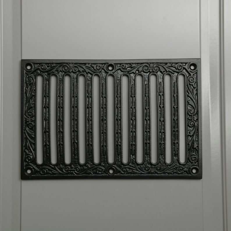 May include: Black cast iron vent cover with a decorative floral design and vertical bars.