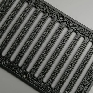 May include: Black cast iron vent cover with an ornate design. The cover has multiple rectangular openings and a decorative border.