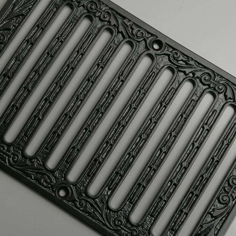 May include: Black cast iron vent cover with an ornate design. The cover has multiple rectangular openings and a decorative border.