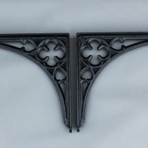 Könnte beinhalten: Zwei schwarze Schmiedeeisen-Regalhalterungen mit einem dekorativen Vierpass-Design. Die Halterungen sind gebogen und haben einen traditionellen Stil.