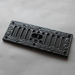 May include: Black cast iron vent cover with a decorative floral design and a rectangular opening.