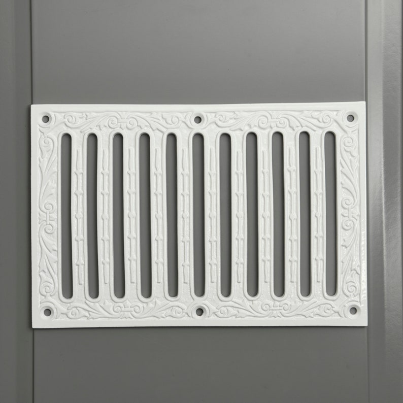 May include: White decorative vent cover with a floral design and a series of vertical slots.