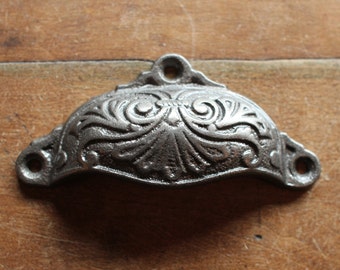 May include: A silver cast iron drawer pull with a decorative floral design.