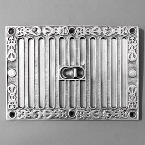 May include: A silver metal vent cover with a decorative border and a rectangular grille. The vent cover has a small, rectangular, metal damper.
